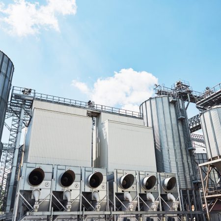 Agricultural Silos. Building Exterior. Storage and drying of grains, wheat, corn, soy, sunflower against the blue sky with white clouds.
