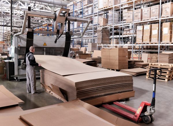 A worker processes furniture blanks on a complex technological machine at a factory. Industrial production of furniture